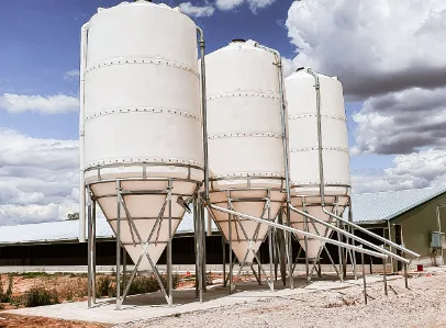 Three raised-frame poly silos connected to feed augers on a rural property